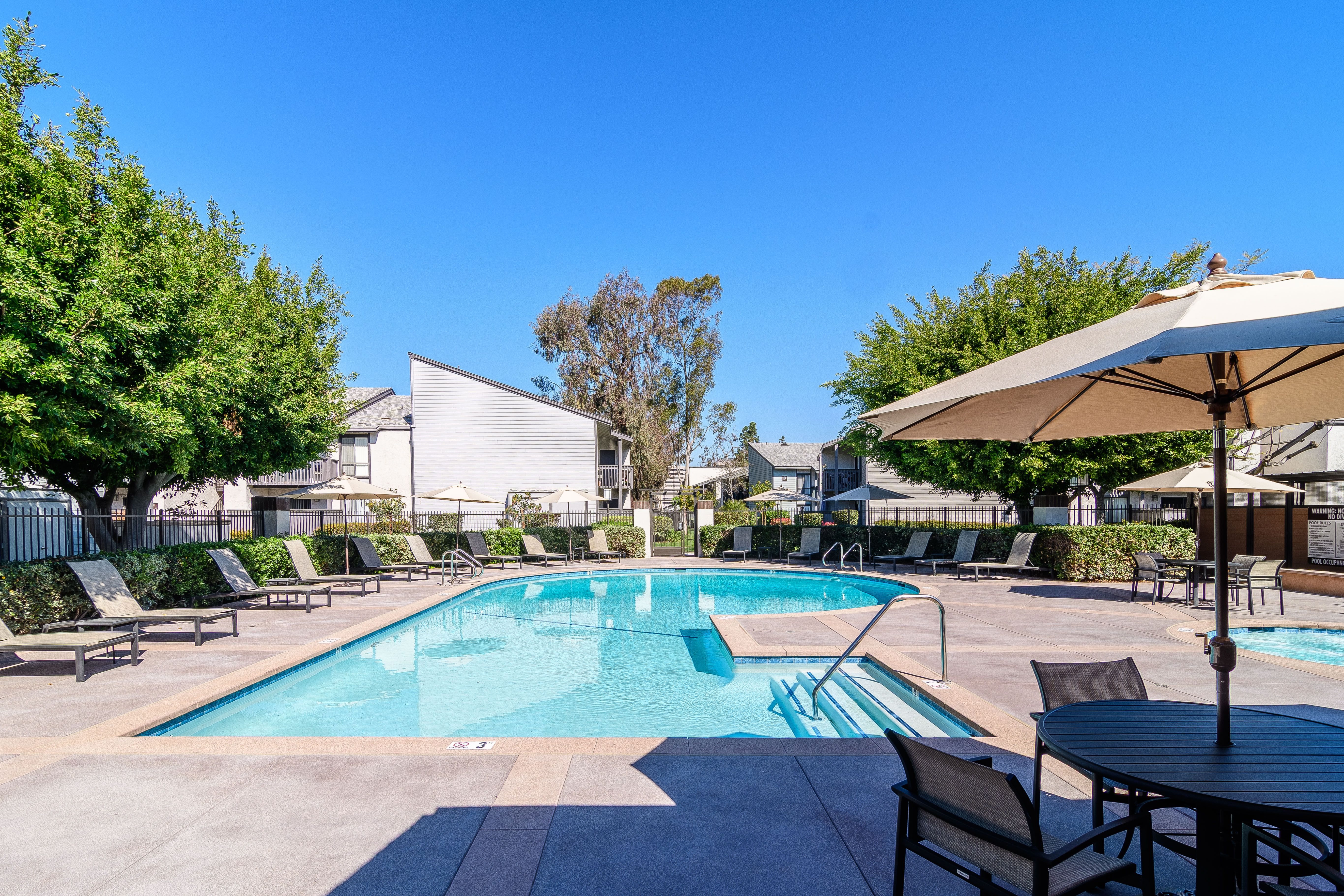 A pool surrounded by chairs and umbrellas.
